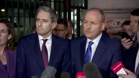 Simon Harris, left, and Micheál Martin right, are giving a press converence and both wearing suits and ties.