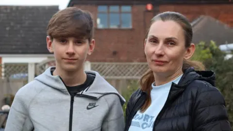 A view of Viktoriia and Ivan stood in their garden, looking at the camera for a photo.