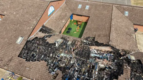 An aerial shot shows fire damage to the roof of a school.