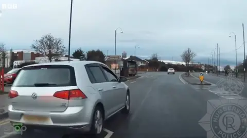 A near miss recorded on dashcam camera showing a silver VW car undertaking another car on a residential road.