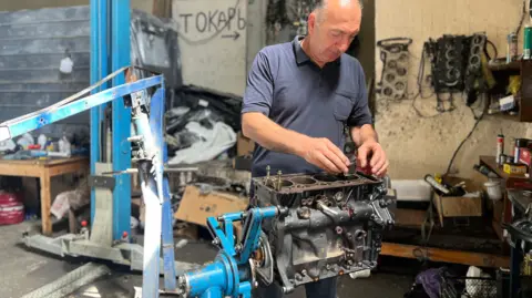 Car mechanic Zaza Andreashvili works on an engine.