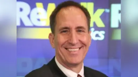 Lifeward Lifeward CEO, Larry Jasinski smiles at the camera. We see his head and shoulders as he wears a dark suit and a shirt and has short dark hair.