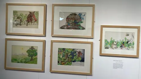 Jon Wright/BBC Five pictures in frames on a gallery wall, showing colourful creatures and a large tree.