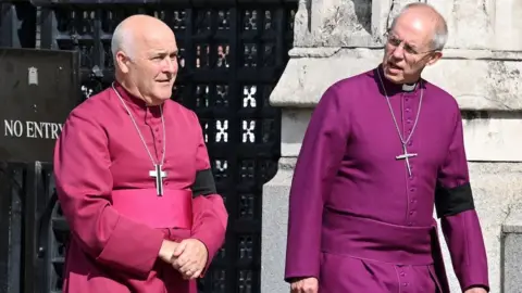 Reuters Uskup Agung York, Stephen Cottrell, dan mantan Uskup Agung Canterbury, Justin Welby, berbicara satu sama lain ketika mereka meninggalkan Gedung Parlemen. Mereka berdua mengenakan jubah ungu tradisional tokoh senior Gereja Inggris, dengan salib digantung di liontin di leher mereka.