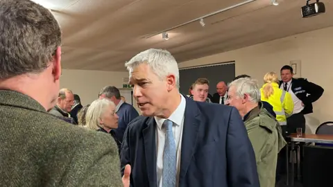 John Devine/BBC MP Steve Barclay with white hair talking to people in a room