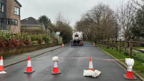 BBC/Sam Dixon-French A lorry on a closed off part of the road pumping water 