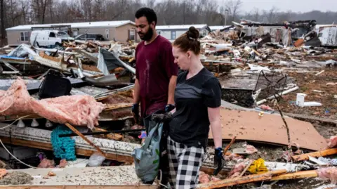 A brother and sister search through her destroyed home at a trailer park in Poplar Bluff, Missouri