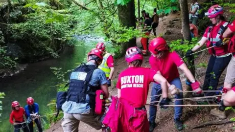 Buxton Mountain Rescue team lowering a volunteer and a paramedic towards a river.