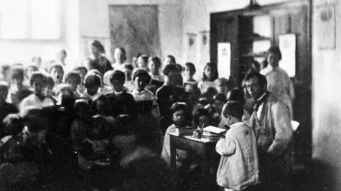 Getty Images/ Colonel H.W Verschoyle A black and white image showing a school in the 1800s