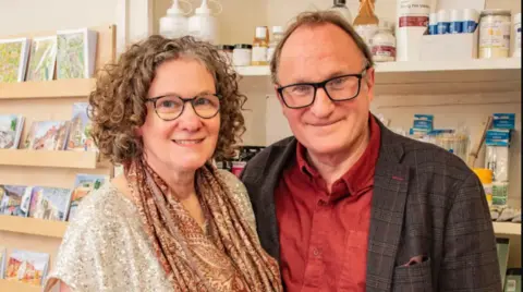 David Drake Man and woman stood smiling in a shop