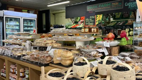 Image of Park Farm shop. You can see punnets of blueberries, cakes and fresh fruit and vegetables.