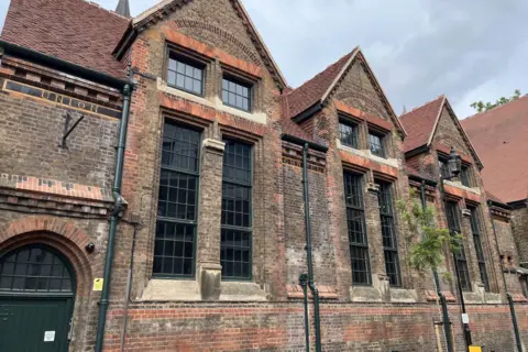 The brick exterior of the Sunday School with large tall windows in three sections along the façade of the building