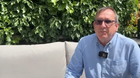 Russell Barton sitting on outdoor furniture in his garden.