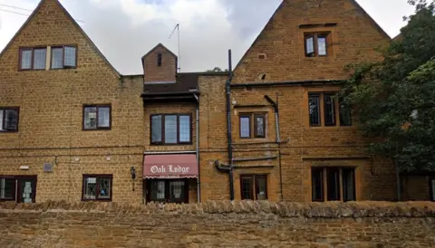 Google Side view of three-story brick-built care home with Oak Lodge sign above window
