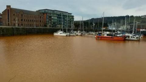 A general view of Whitehaven Harbour with brown water surrounding the boats