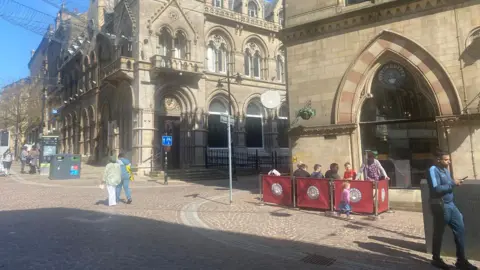 BBC/Grace Wood People sit outside a cafe on Bridge Street in the centre of Bradford