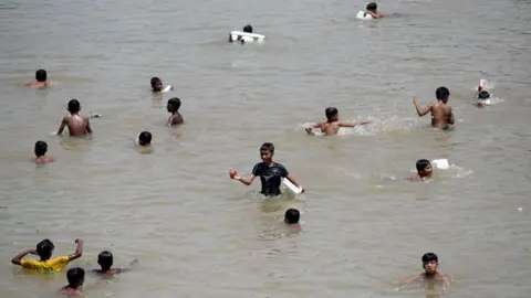 Getty Images Children cool off in a lake on a hot day in Dhaka