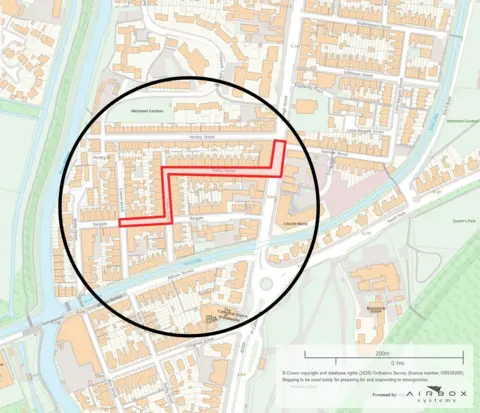 Lincolnshire Police A detailed street map of a part of Lincoln. A thick black circle highlights part of the neighbourhood, and a bold red line traces an angular route through several streets within the circle - starting on the left, turning sharply upward, then continuing to the right. Roads, buildings, a canal, and green spaces are visible around the highlighted area.