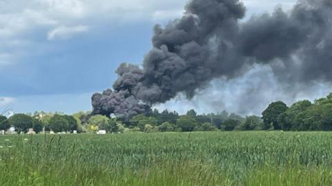 Black smoke drifting over a field