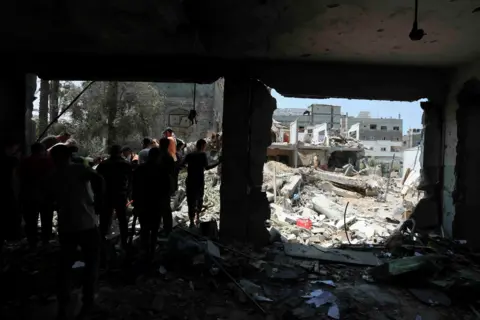 Reuters People leave a school hit by an Israeli strike in Gaza