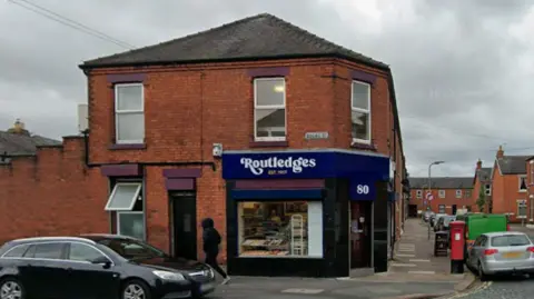 Google An exterior view of Routledges The Bakers, a red brick building with a dark blue sign that reads 'Routledges, est. 1917'.
