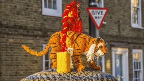 A knitted tiger on a postbox celebrates the Year of the Tiger in the Chinese zodiac calendar. It is orange and black.