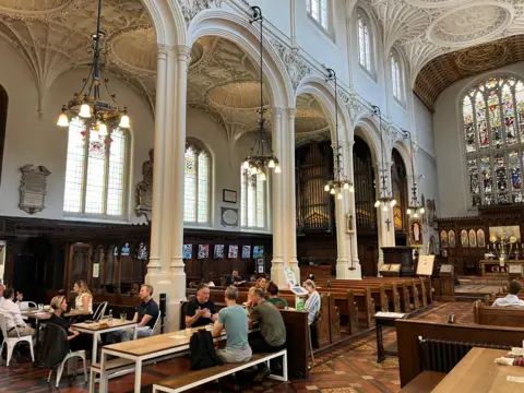 The interior of a church and people sitting, using it as a cafe space 