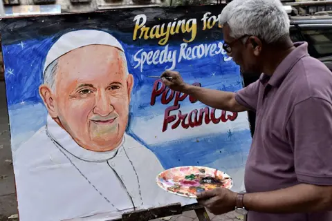 Getty Images A man paints a poster of Pope Francis in Mumbai, India, on 24 February 2025.
