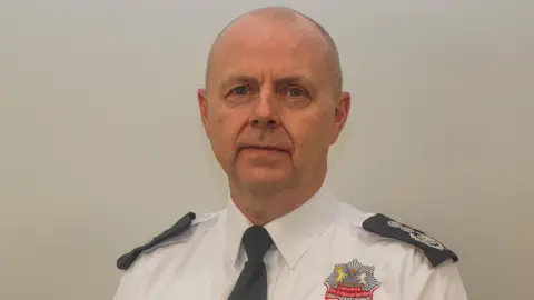 Mick Sharman in a white shirt and black tie