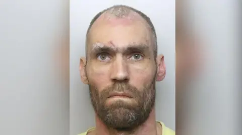 Mugshot of convicted sex offender Robert Emmerson. He has short, receding and greying hair and a beard.