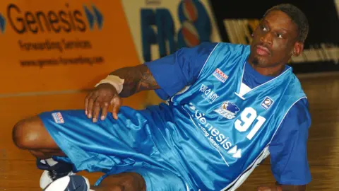 Getty Images Dennis Rodman in a blue Brighton Bears kit. He is getting up off the floor.