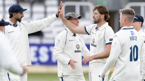 Ben Aitchison high fives a Derbyshire team-mate after taking a wicket against Middlesex at Lord's
