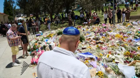 FLAVIO BRANCALEONE/EPA/Shutterstock Members of the public stand in front of a floral tribute