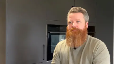Pete Evans whose son was educated out of school by Remedicare, seated in the family home.