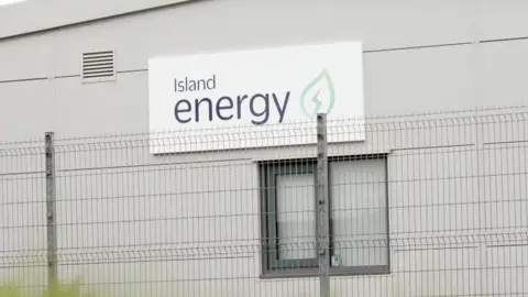 An Island Energy sign on a warehouse, with a fence in front of it.