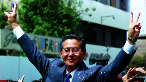 Reuters Peruvian President Alberto Fujimori makes a victory sign with his inked fingers after voting in the country's first-ever constitutional referendum on October 31, 1993.