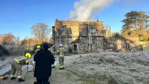 OFRS Firefighters tackling the blaze at Bignell House during the day. Smoke is seen coming from the roof.
