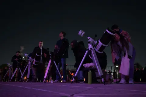 AFP People line up with telescopes to watch the moon