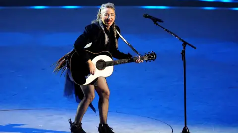 PA Media KT Tunstall in black outfit and playing a guitar as she sings on stage