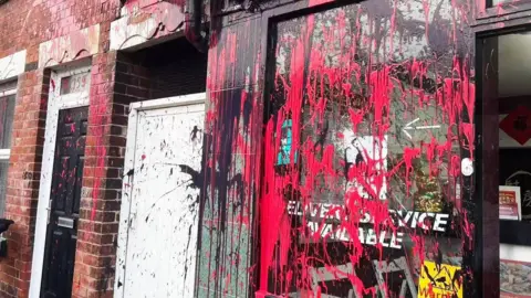 Supplied A Chinese takeaway and neighbouring terraced house splattered with red and black paint. The paint covers the window of the shop, the white gate between the shop and the house, the neighbour's black door and the brickwork.