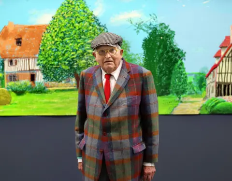 AFP via Getty Images British painter David Hockney poses at the Orangerie museum in Paris, on October 7, 2021, in front of his painting "A year in Normandy", a 91-meter-long artwork painted during the lockdown in 2020.