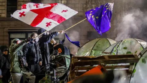 Georgian opposition supporters wave EU and Georgian flags during a protest in front of Parliament building in Tbilisi, Georgia