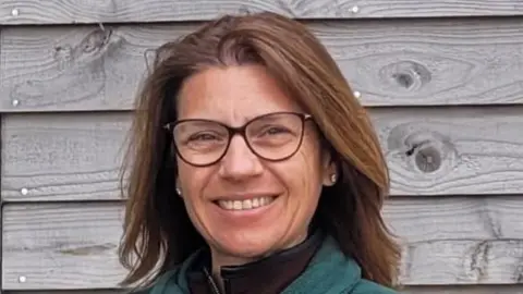 The Country Food Trust A woman with glasses and brown hair smiling at the camera.
