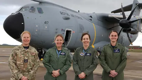 RAF Four women in RAF uniform stood in front of a large grey plane