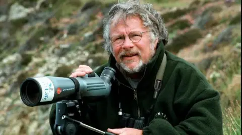 Bill Oddie out watching birds with a telescope