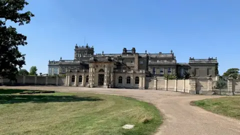 BBC Shrubland Hall is a large historic building which has a large driveway in front of it. The building has a main entrance in the middle.