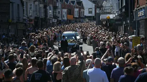 Getty Images A large crowd is seen gathered around Bonnie Tyler's coffin