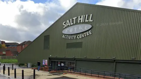 Salt Hill Activity Centre is a triangular, dark green building with a few steps leading down to the main entrance.