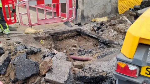 An area of dug up and broken Tarmac.