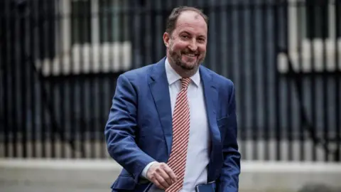 Getty Images A smiling Guto Harri wearing a blue suit and striped tie walking down Downing Street